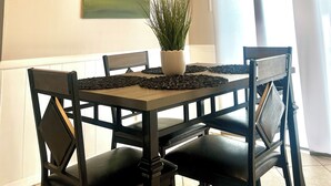 A dining area with a table, chairs, a potted plant, and a ceiling light fixture.