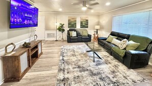 A modern living room with a flat-screen TV, a sofa, a coffee table, and a patterned rug.