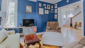 A living room with a blue wall, a flat-screen TV, a beige armchair, and a white sofa.