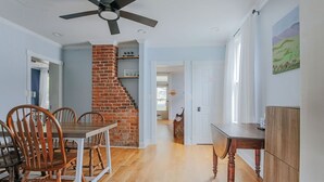 Un coin repas agrémenté d’une cheminée en briques, de chaises en bois et d’un ventilateur de plafond.