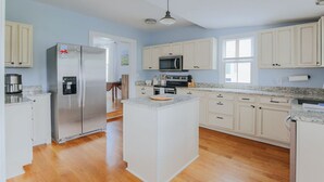 A modern kitchen with white cabinets, stainless steel appliances, and a central island.