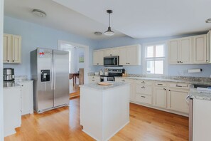 Een moderne keuken met witte kasten, roestvrijstalen apparatuur en een centraal eiland.