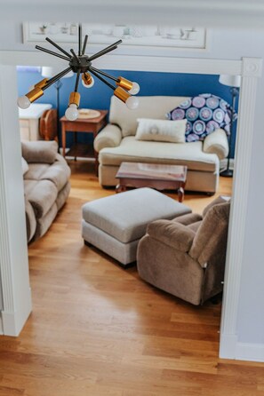 Una sala de estar moderna con sofá, reposapiés y una lámpara de techo original.