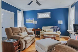 Ein Wohnzimmer mit blauer Wand, zwei Sofas, einem Couchtisch und einem Fernseher.