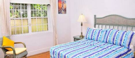 Une pièce avec un lit, une chaise, une fenêtre avec des rideaux et une lampe.
