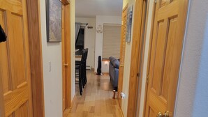 En hall med trädörrar, en matplats med stolar och en soffa.