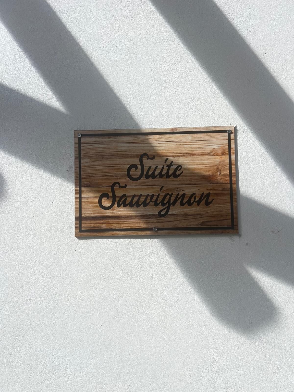 A wooden sign with the text "Suite Sauvignon" against a white wall.