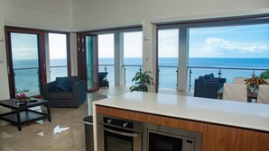 A modern kitchen with a large island, a dining area with a view of the sea, and a cozy seating area with a sofa and a coffee table. - Villa Vino Lucia & Helen's Wine Cellar (Marigot Bay)