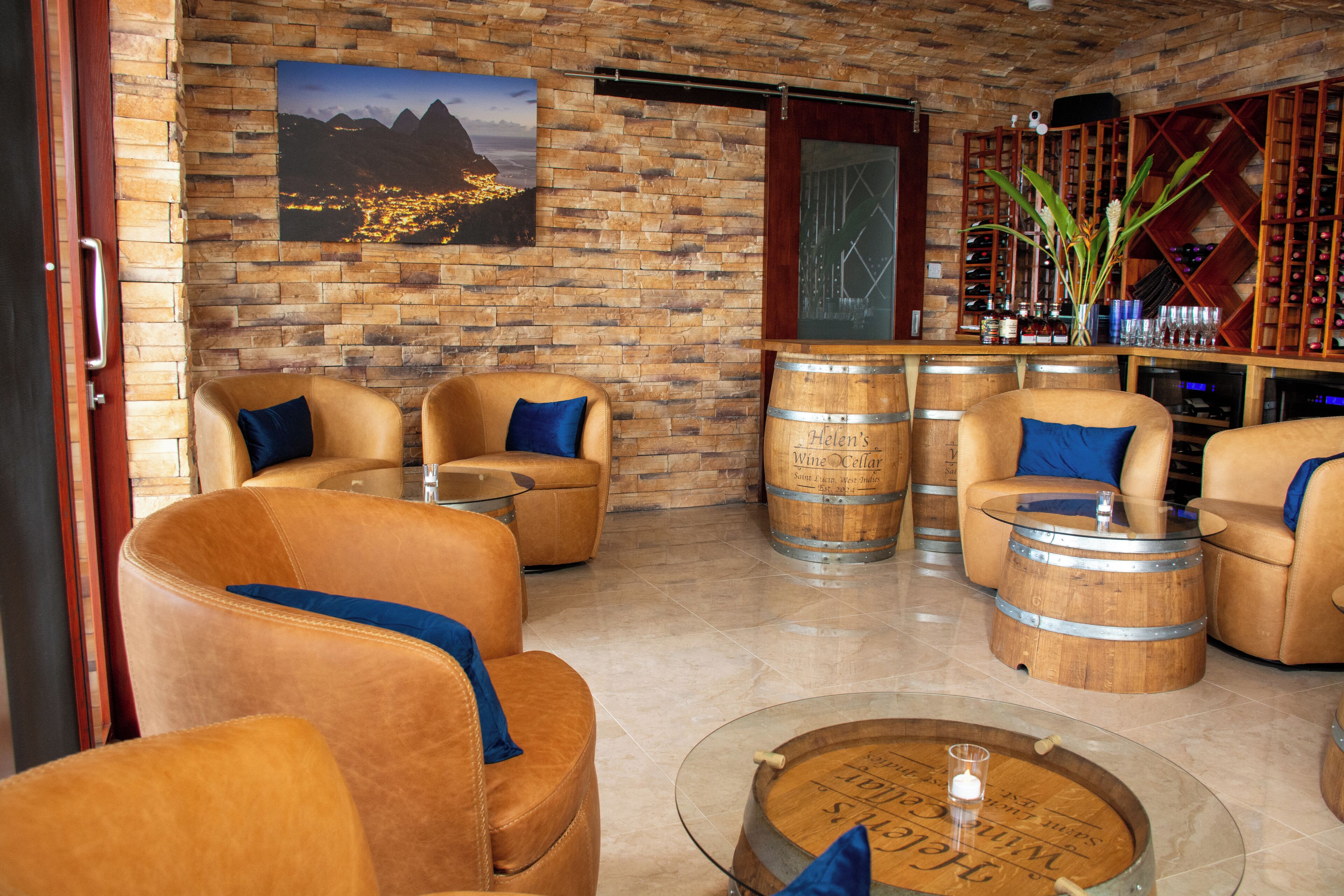 Eine gemütliche Lounge mit Ledersesseln, einem Glastisch und Weinfässern mit der Aufschrift 'Helen's Wine Cellar'.