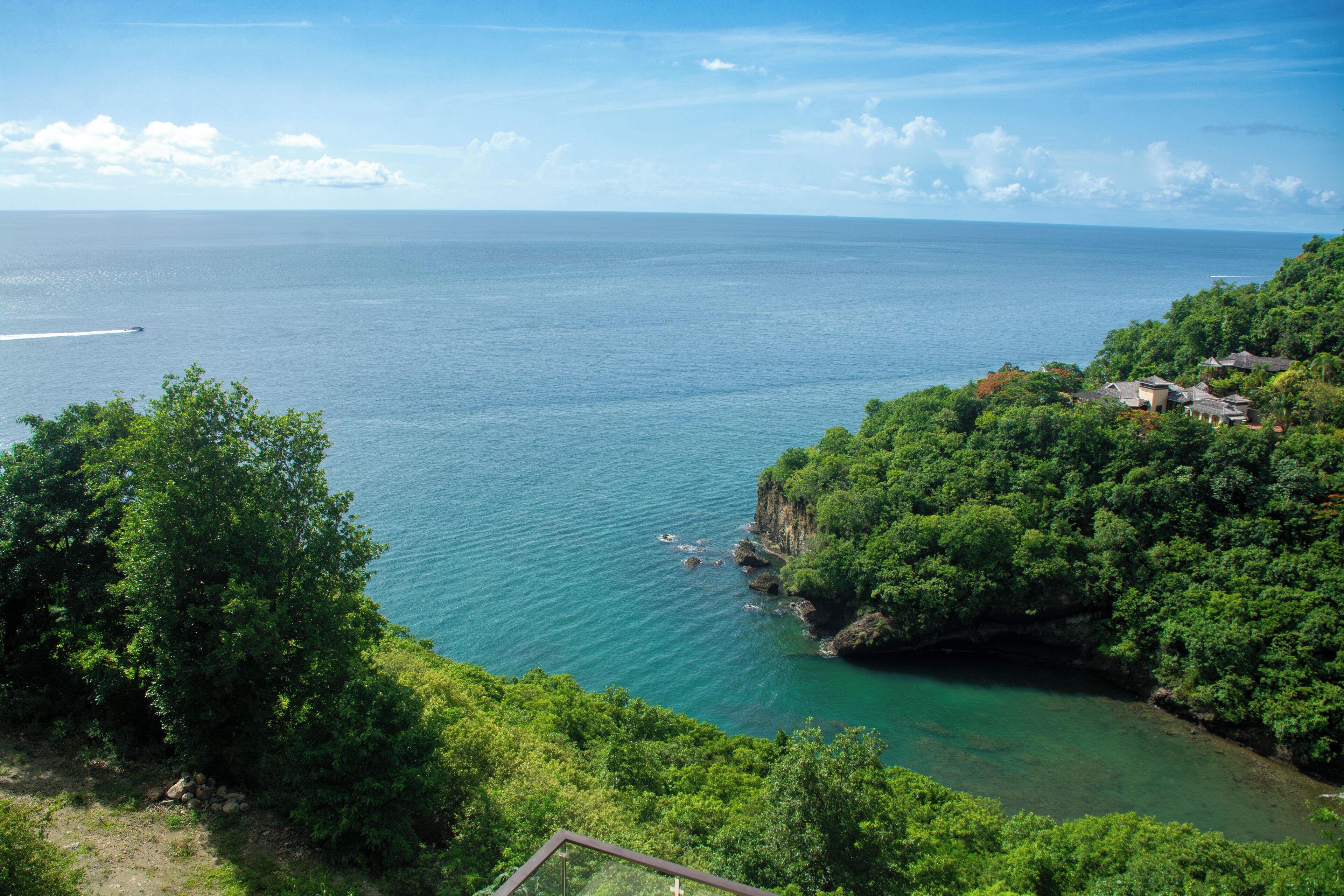 Un paysage côtier offrant une vue dégagée sur la mer, une végétation luxuriante et quelques bâtiments situés sur une colline.