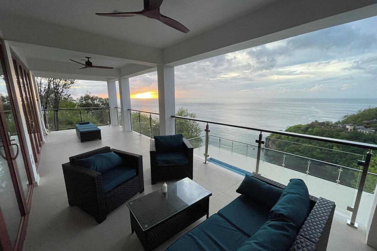 A spacious balcony with a view of the sea, furnished with sofas and a table.