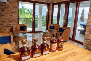Una habitación con sofás de cuero, una mesa de madera con botellas de licor y una mesa de centro con superficie de vidrio.