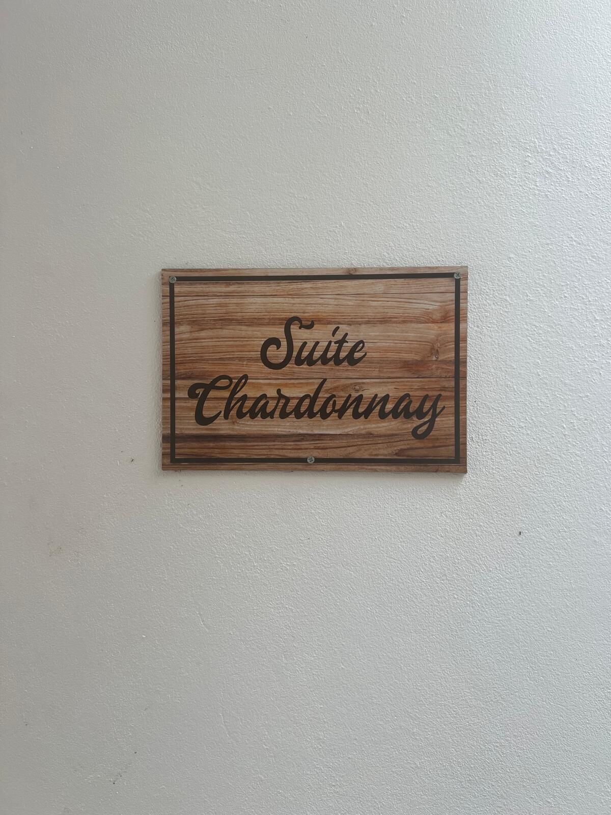 Un letrero de madera con el texto 'Suite Chardonnay' colgado en una pared.