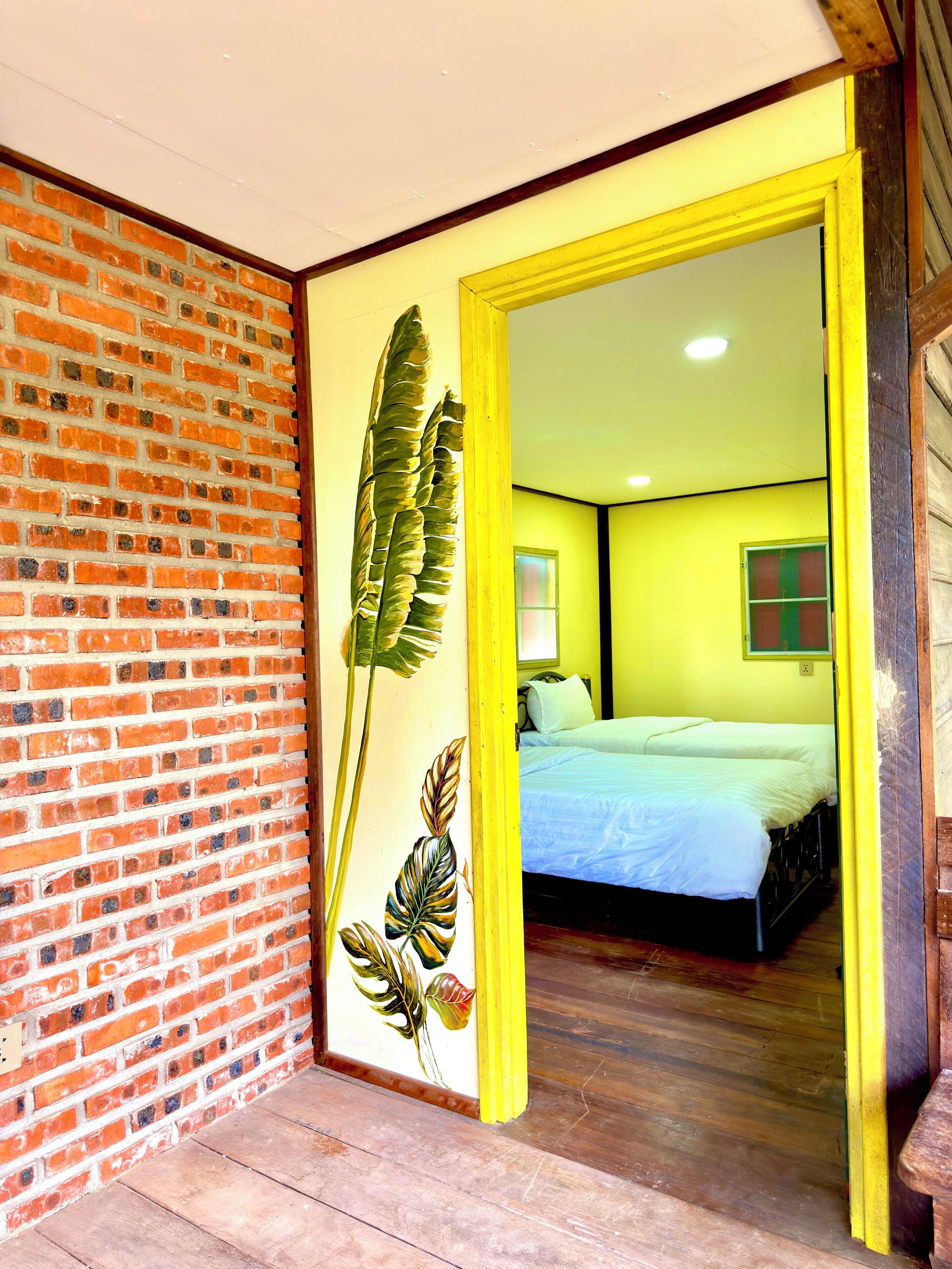 A room with a brick wall, a bed with a blue bedspread, and a yellow door frame.