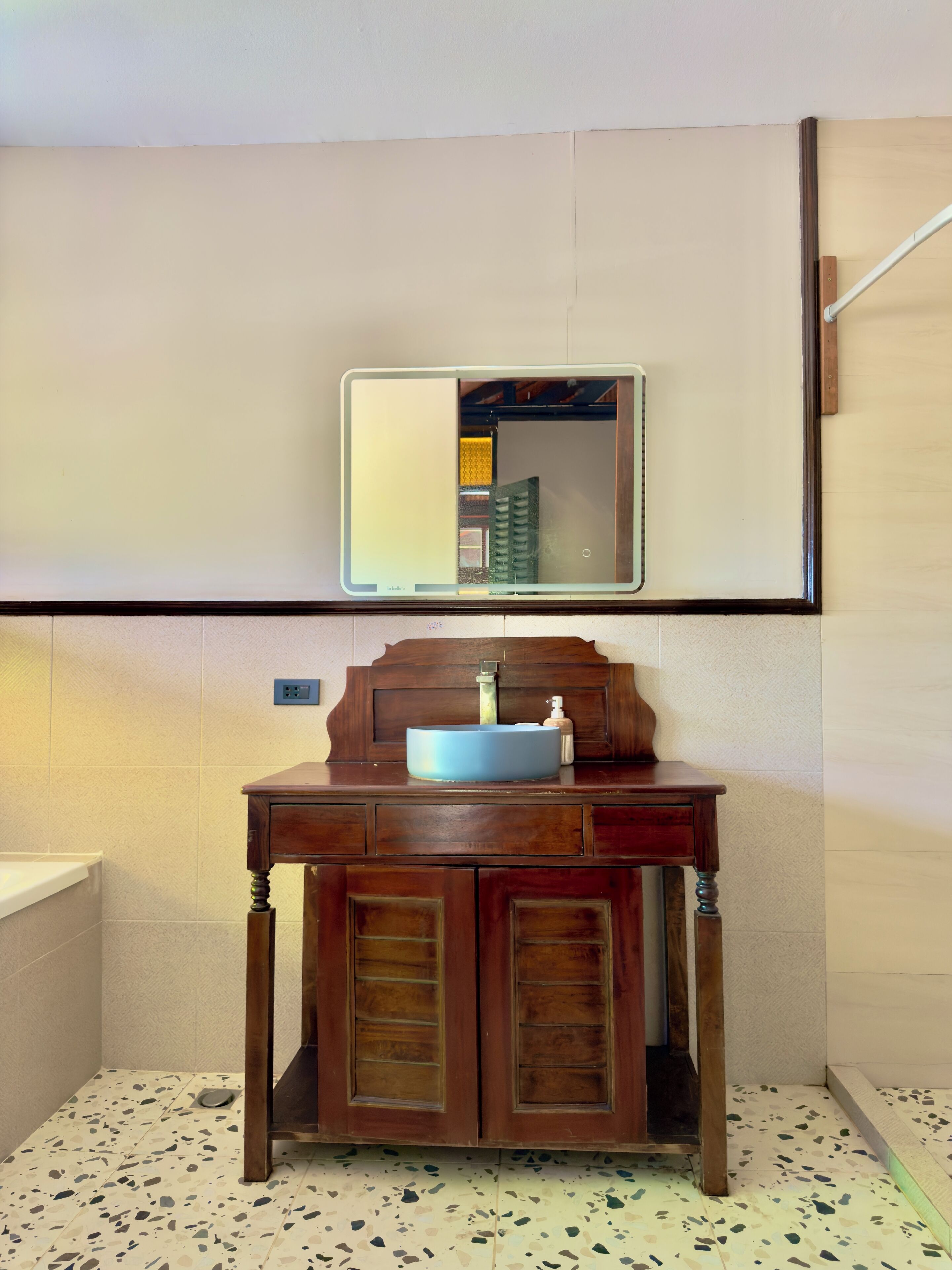 A bathroom with a wooden vanity, a mirror, and a sink.