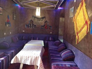 A room with a long table and several sofas arranged around it. - Kasbah Ifri (Souk Lakhmis Dades)