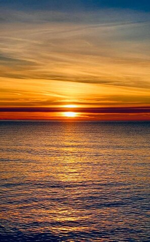 Un atardecer sobre un mar tranquilo con un horizonte despejado.