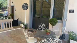 An outdoor seating area with a table and four chairs, a small potted plant, and a door with a sign. - B&B l'angoletto (Trebisacce)