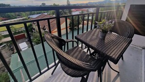 A balcony with wicker furniture and a potted plant, overlooking a residential area with houses and a green space. - A spacious Studio apartment / condo near Clark Airport angeles city pampanga (Angeles)
