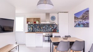 Een moderne keuken met witte kastjes, een houten aanrecht en een eethoek met een tafel en stoelen.