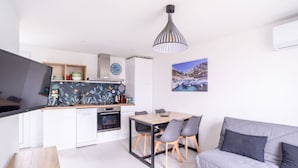 Een compacte woonruimte met kitchenette, eethoek en een slaapbank.