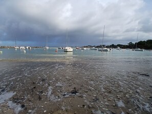 Una playa con barcos anclados en el agua y un litoral rocoso.
