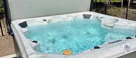 Uma banheira de hidromassagem com tampa, cercada por uma vedação e árvores.