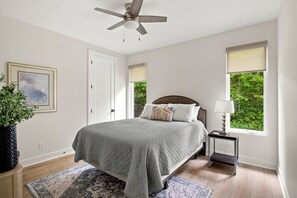 A bedroom with a bed, a ceiling fan, a nightstand with a lamp, a window with a view, and a framed picture on the wall. - SOMETHING FOR EVERYONE,  New 3+ BR, 4 Bath, Ranch, Game Rm, Fenced Yd & Pond (Fennville)