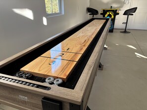 A pool table with a wooden top and black felt, surrounded by a modern room with a window and a bar area. - SOMETHING FOR EVERYONE,  New 3+ BR, 4 Bath, Ranch, Game Rm, Fenced Yd & Pond (Fennville)