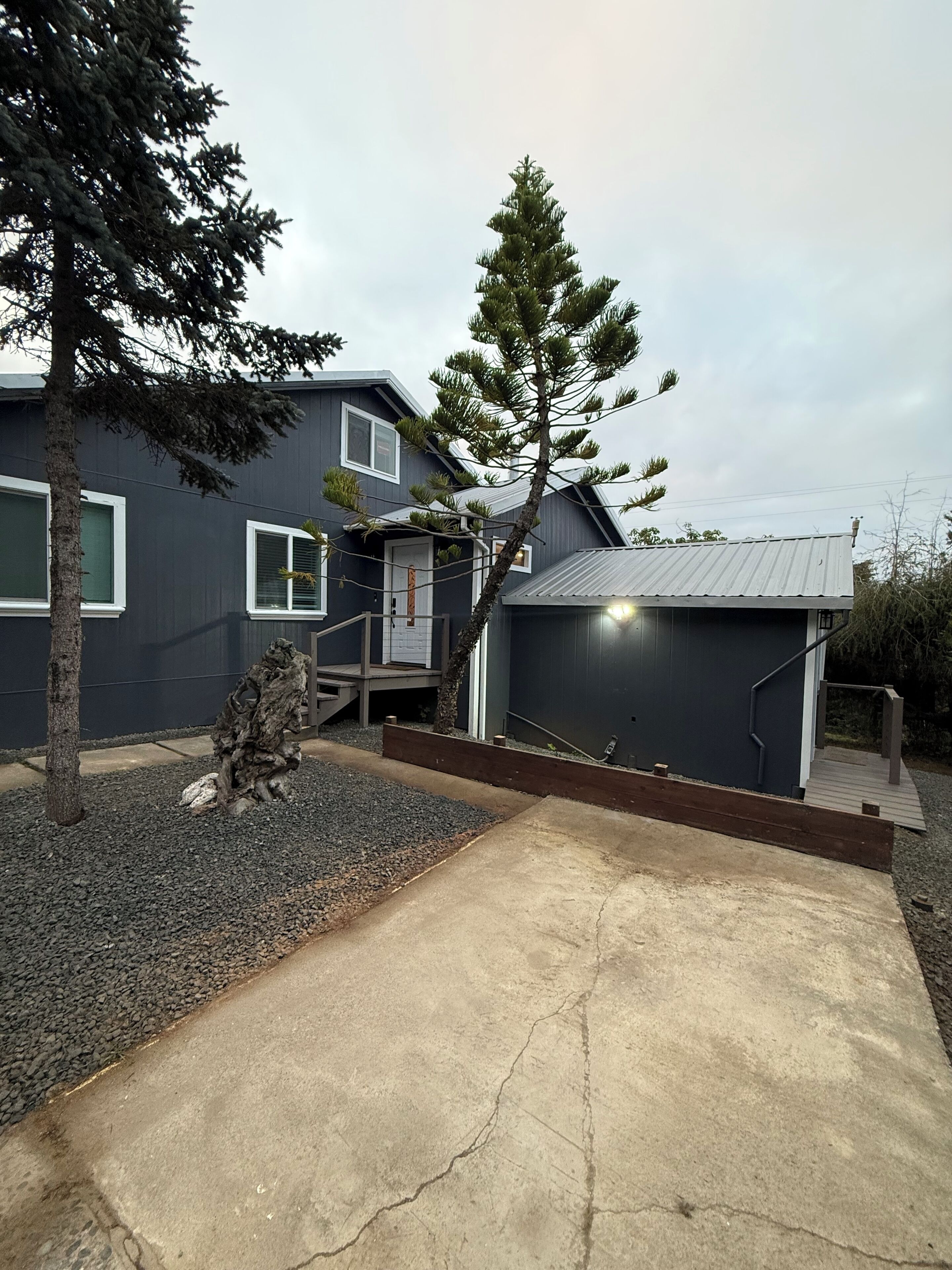 A modern two-story house with a dark exterior, a front porch, and a driveway leading to the entrance.