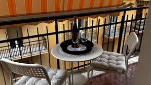 A balcony with a table and chairs, a bottle of wine, and a glass. - Coro & Bentu  (Alghero)