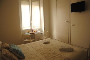 Une chambre à coucher comprenant un lit, un bureau, une chaise et une armoire.