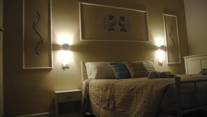 A bedroom with a bed, nightstands, and wall-mounted lights. - Coro & Bentu  (Alghero)