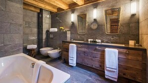 Un baño moderno con una bañera independiente, un tocador doble y un espejo grande.