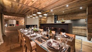 Un comedor moderno con una larga mesa dispuesta para seis comensales, techo de madera y lámparas contemporáneas.