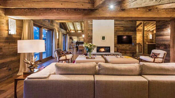 Interior acogedor de una cabaña de madera con chimenea, asientos cómodos y comedor.