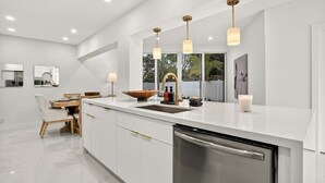 A modern kitchen with a large island, white cabinetry, and pendant lighting. - Delray Oasis: Heated Pool, Spa, Arcade, Sleeps 10 (Delray Beach)