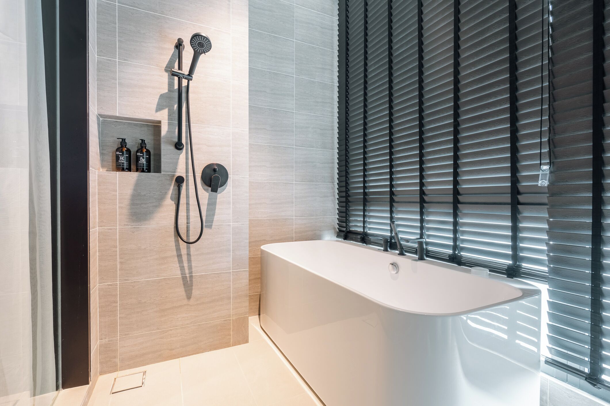 A modern bathroom with a freestanding bathtub, a handheld showerhead, and a built-in shelf with toiletries.