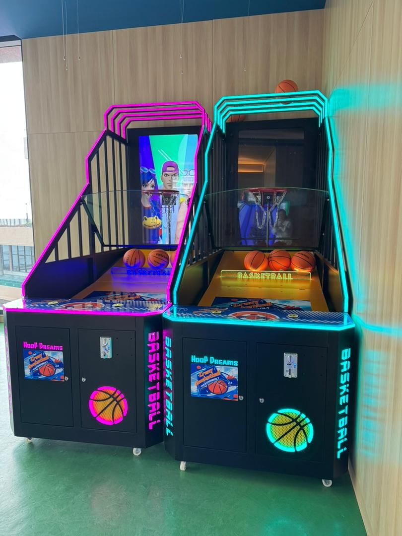 Dos máquinas de baloncesto de arcade con luces de neón, con la etiqueta "BASKETBALL" y "BASKETBALL TRAX".