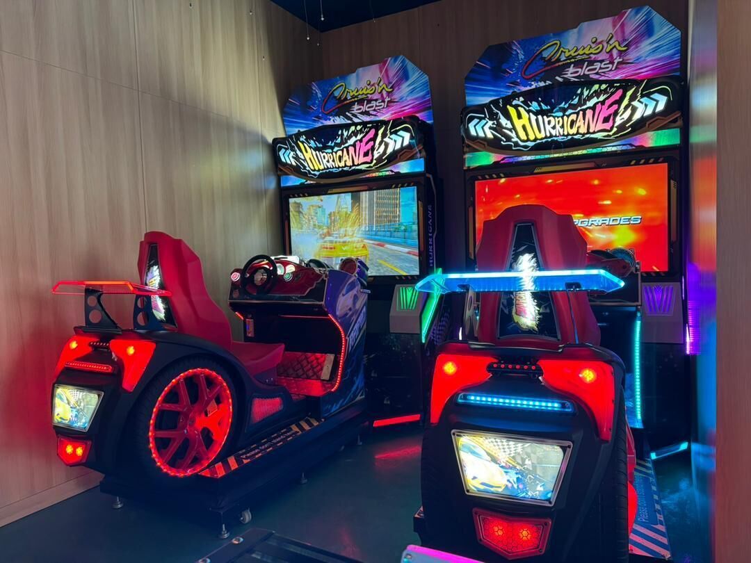 Two racing arcade machines with "Hurricane" branding, red seats, and illuminated controls.
