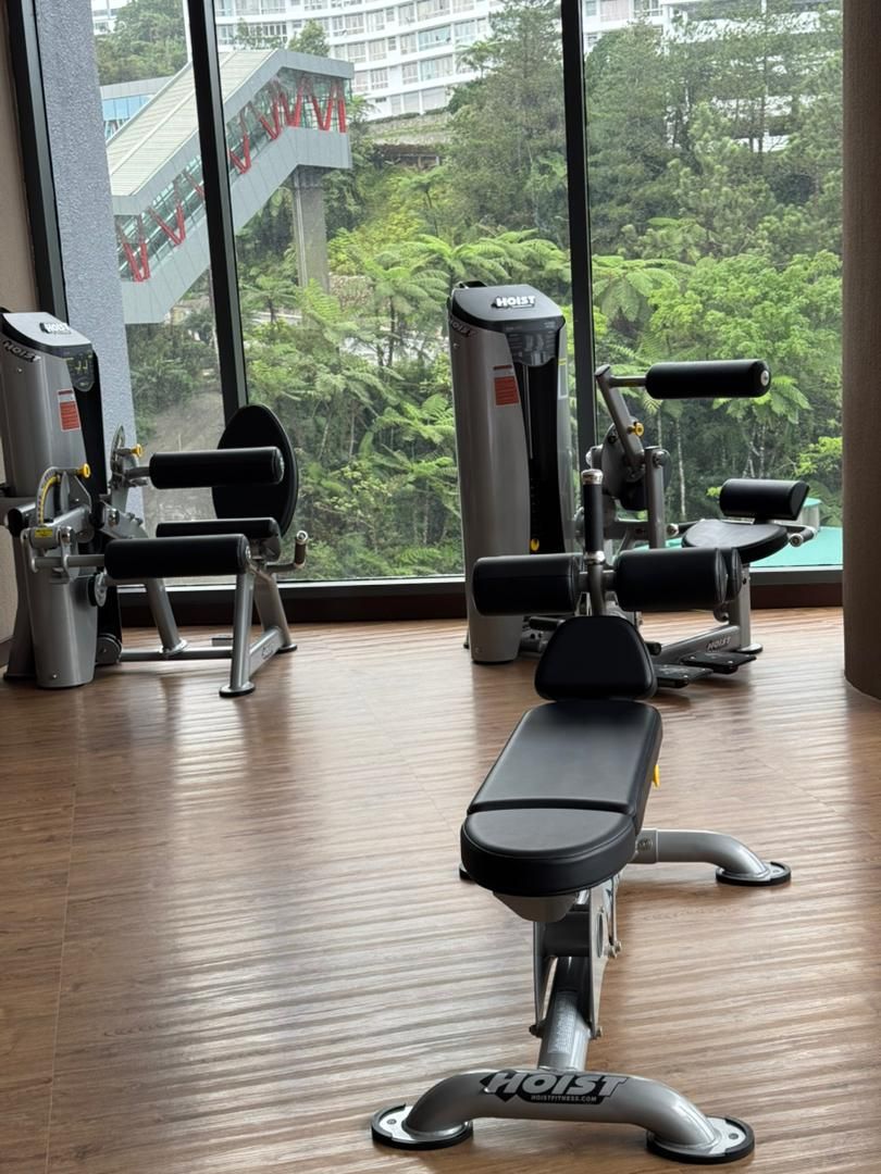 A gym with various exercise equipment, including a bench press, a squat rack, and a cable machine.
