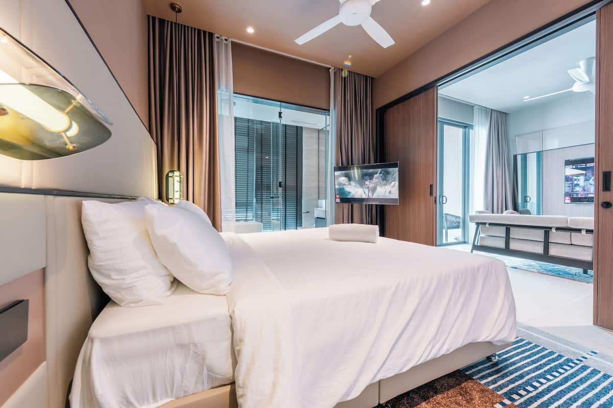 Een moderne hotelkamer met een groot bed, een flatscreen televisie en een plafondventilator.