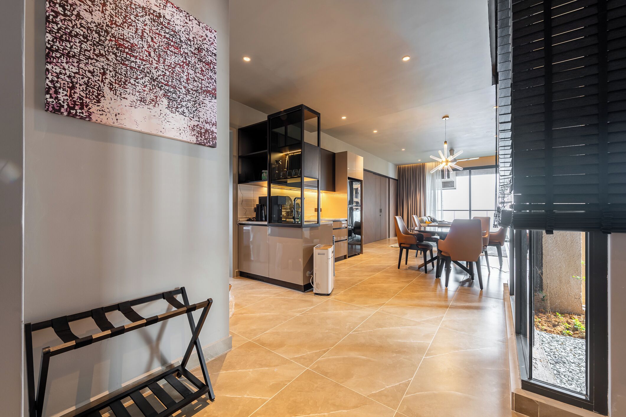 Una cocina moderna con una isla integrada, un comedor con sillas y un amplio ventanal con persianas.