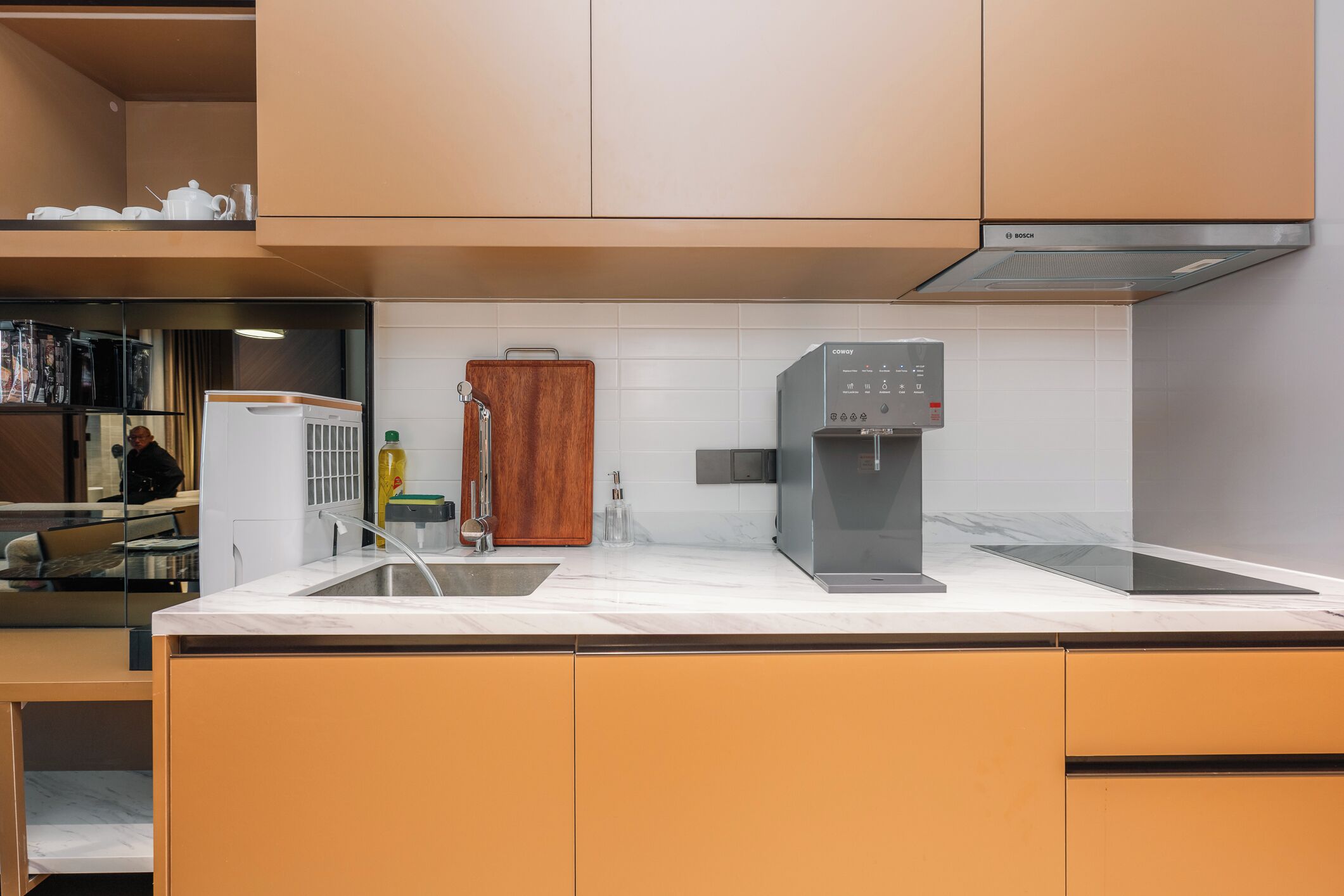 A modern kitchen with a Bosch coffee machine, a wooden cabinet, and a sink.