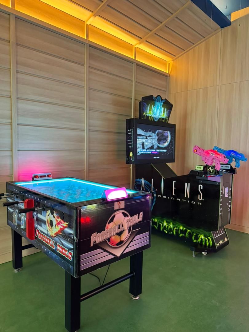 A gaming area with a foosball table, a video game console, and a display of toy guns.