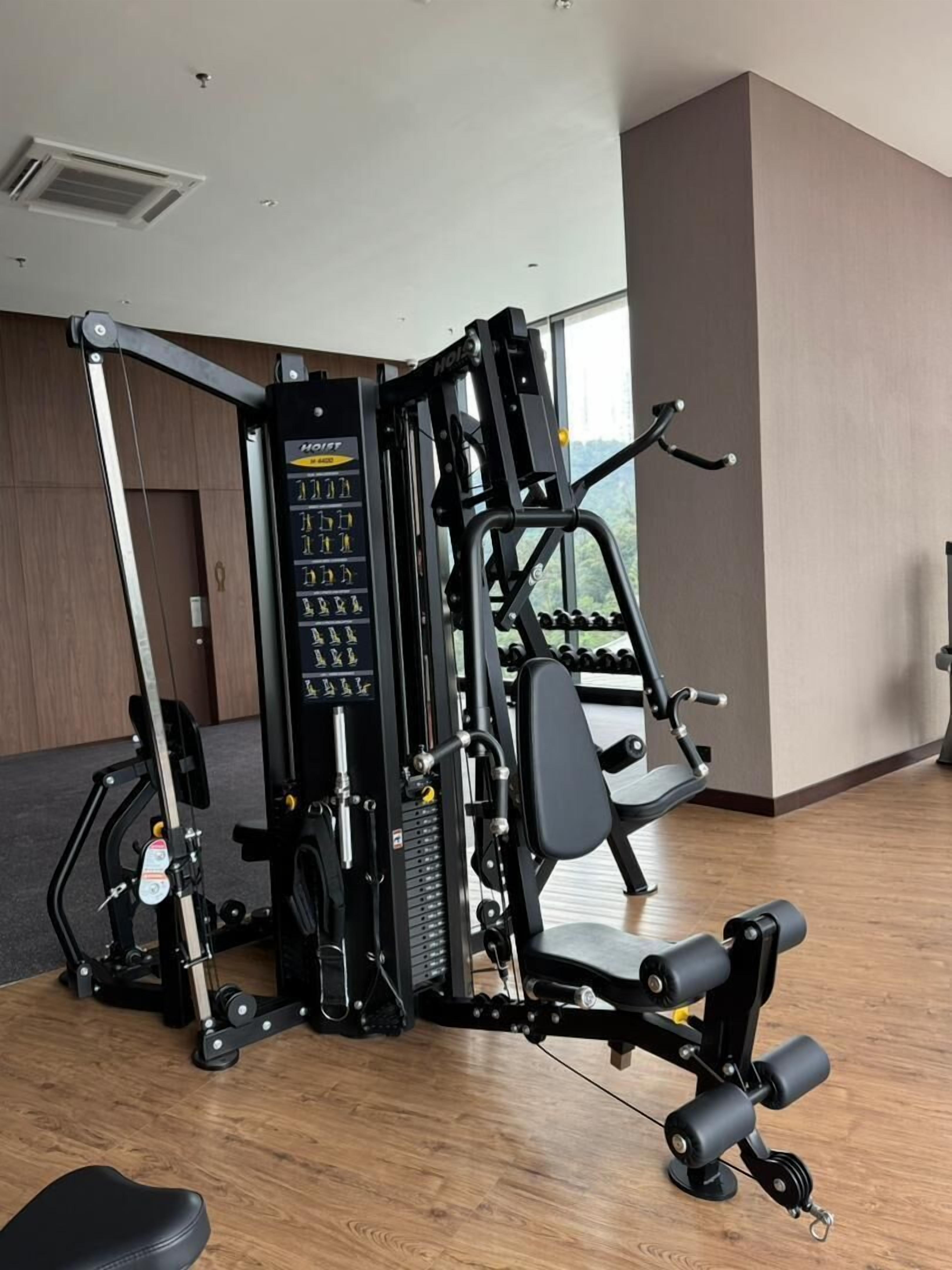 Een sportschool met diverse fitnessapparaten, waaronder een multifunctionele gewichtstapel en een kabelmachine.