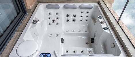 Una bañera de hidromasaje con múltiples chorros, un panel de control y un asiento incorporado.