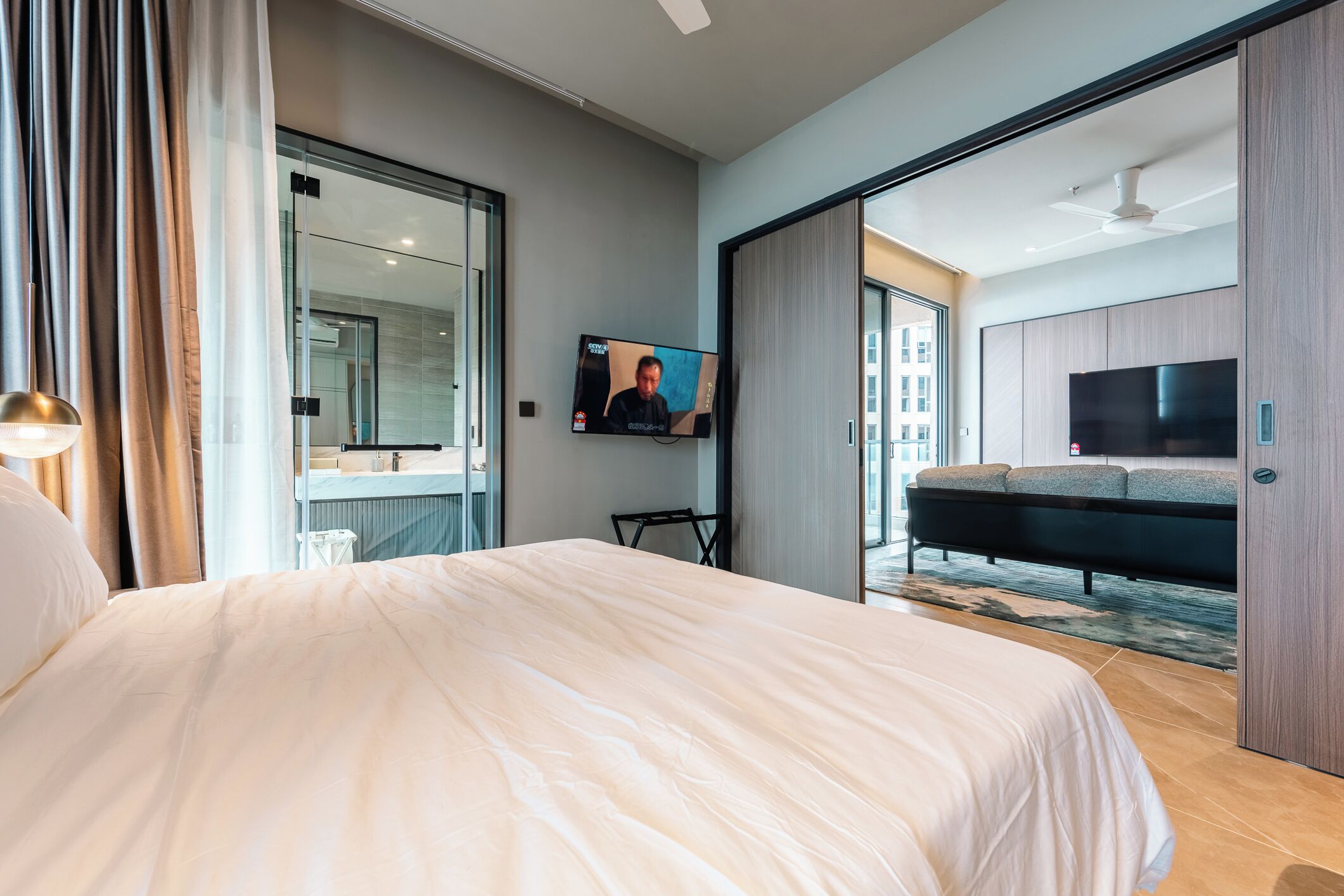 A modern hotel room with a large bed, a flat-screen TV, and a sliding door leading to a balcony.