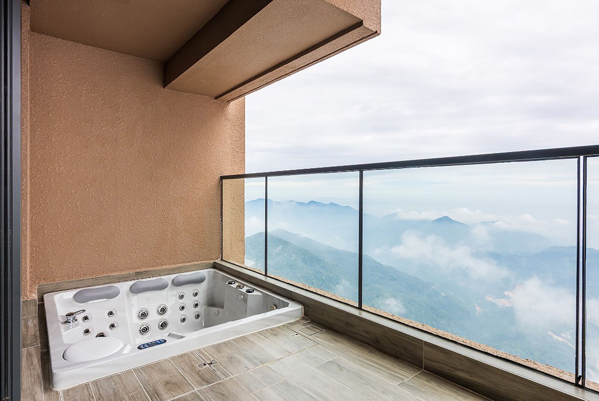 A balcony with a hot tub, a view of mountains, and a modern architectural design.