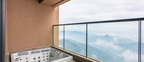 A balcony with a hot tub, a view of mountains, and a modern architectural design.